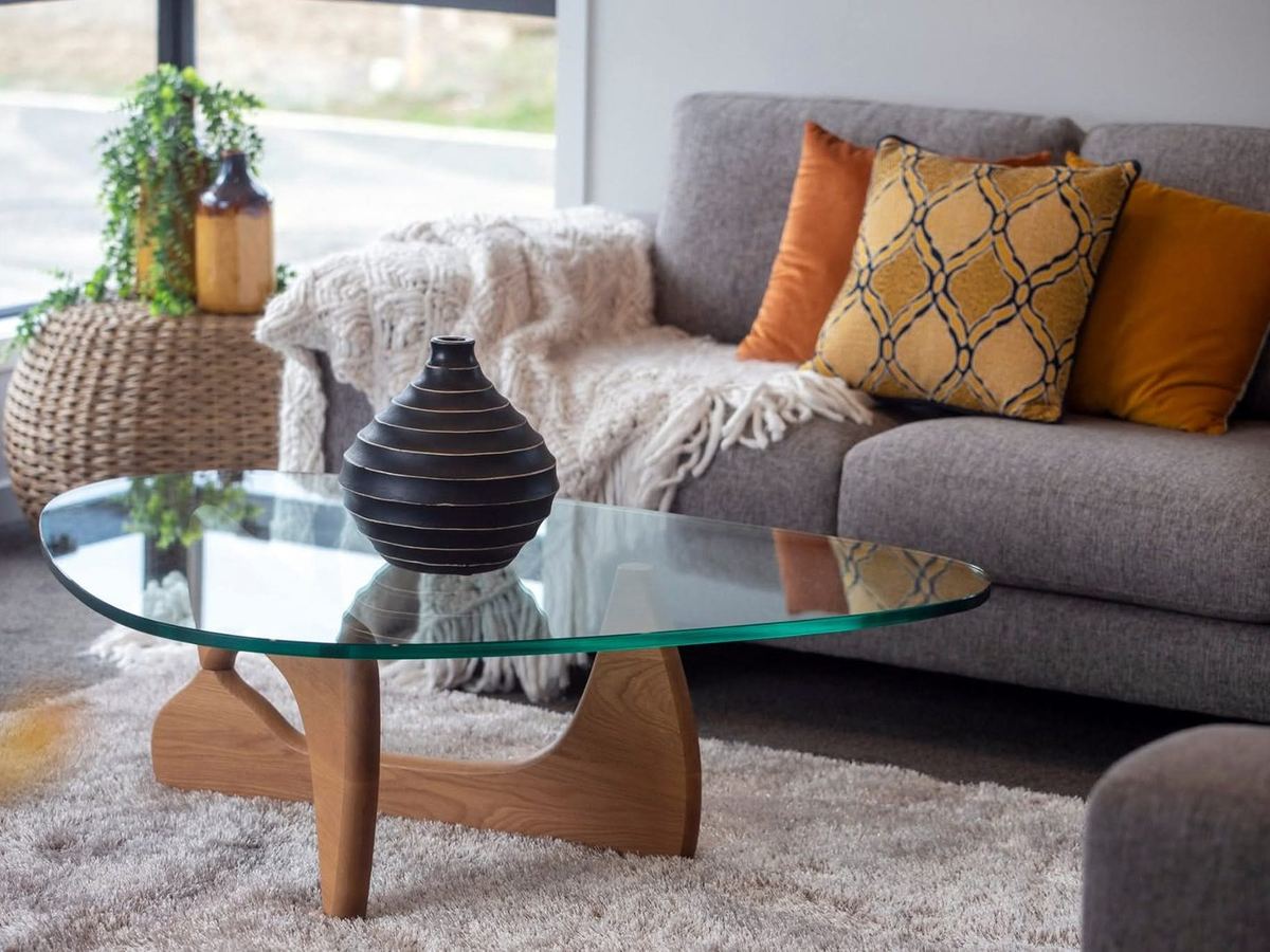 Styled glass coffee table detail with vase and throw