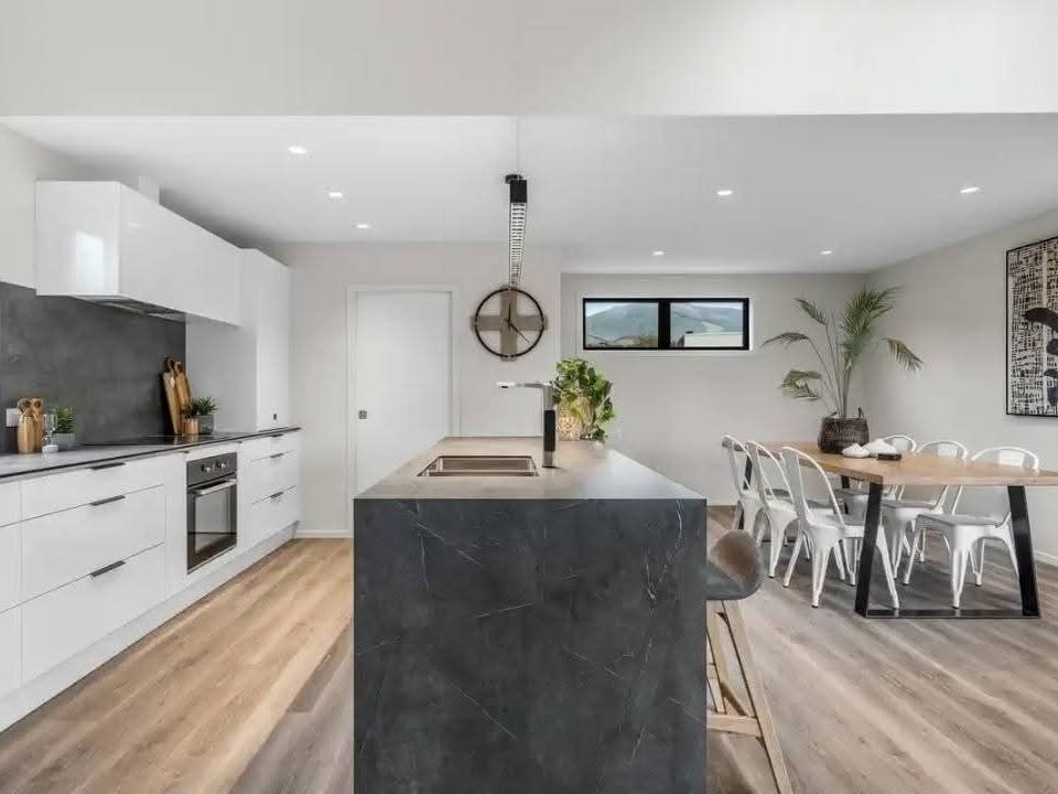 Staged kitchen with dark stone island and dining table
