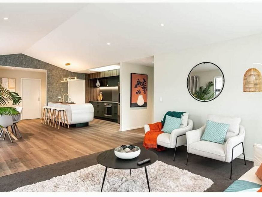 Staged open-plan kitchen and lounge with white armchairs